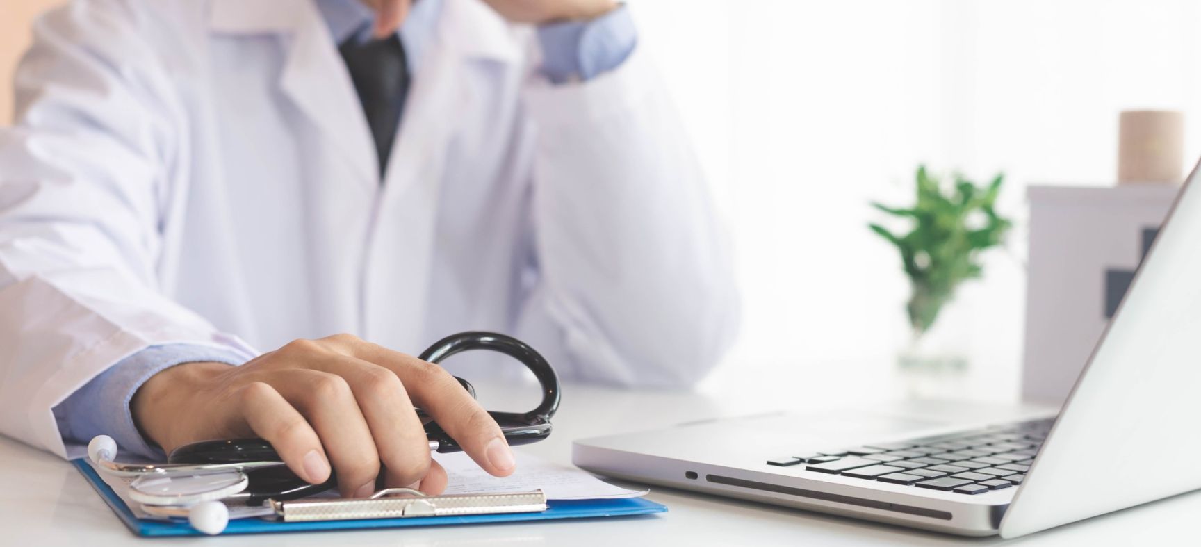 Male asian doctor holding a pen filling patients information